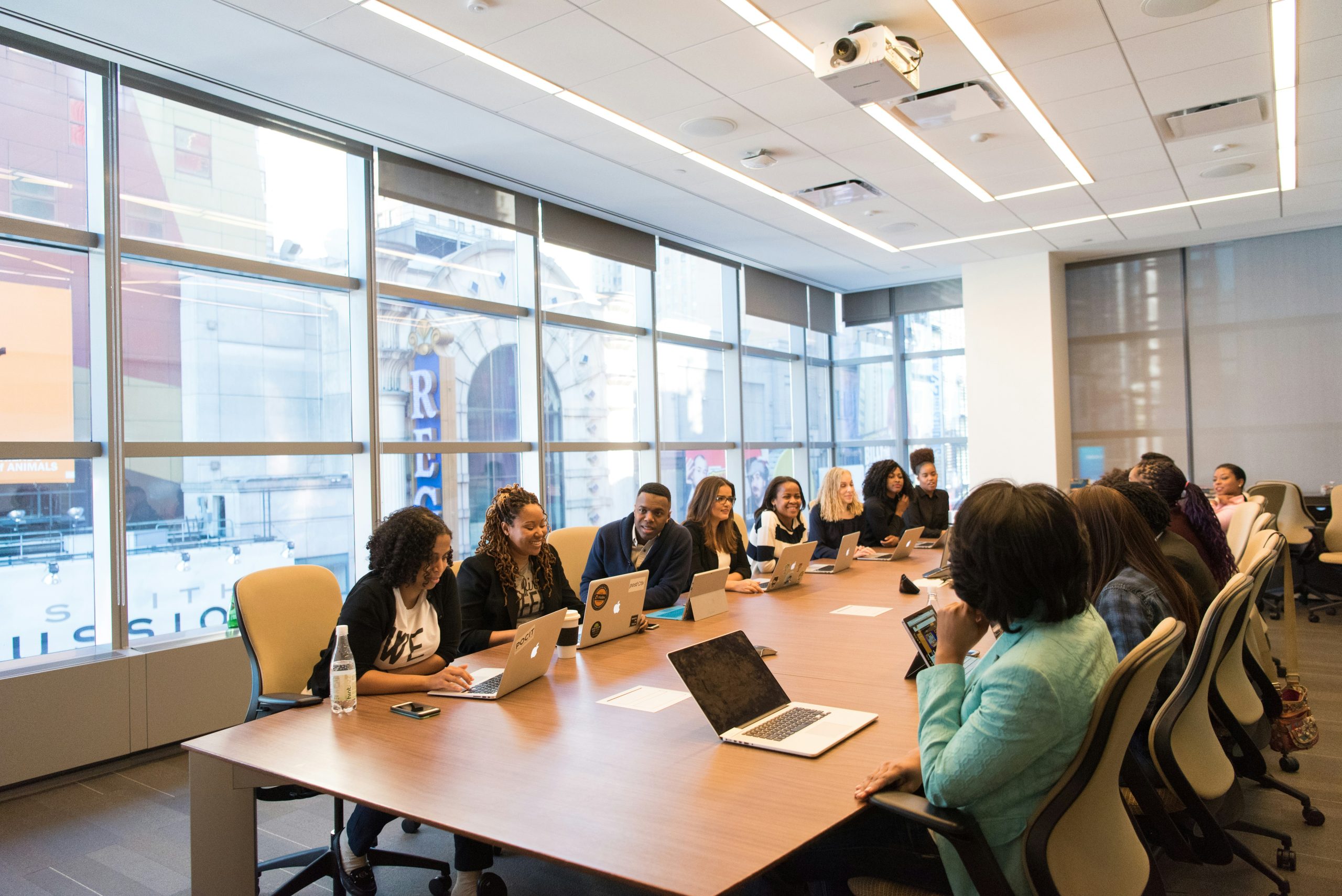 Um grupo de pessoas diversas sentadas ao redor de uma mesa grande, em uma sala de conferências sobre ações de governança corporativa.