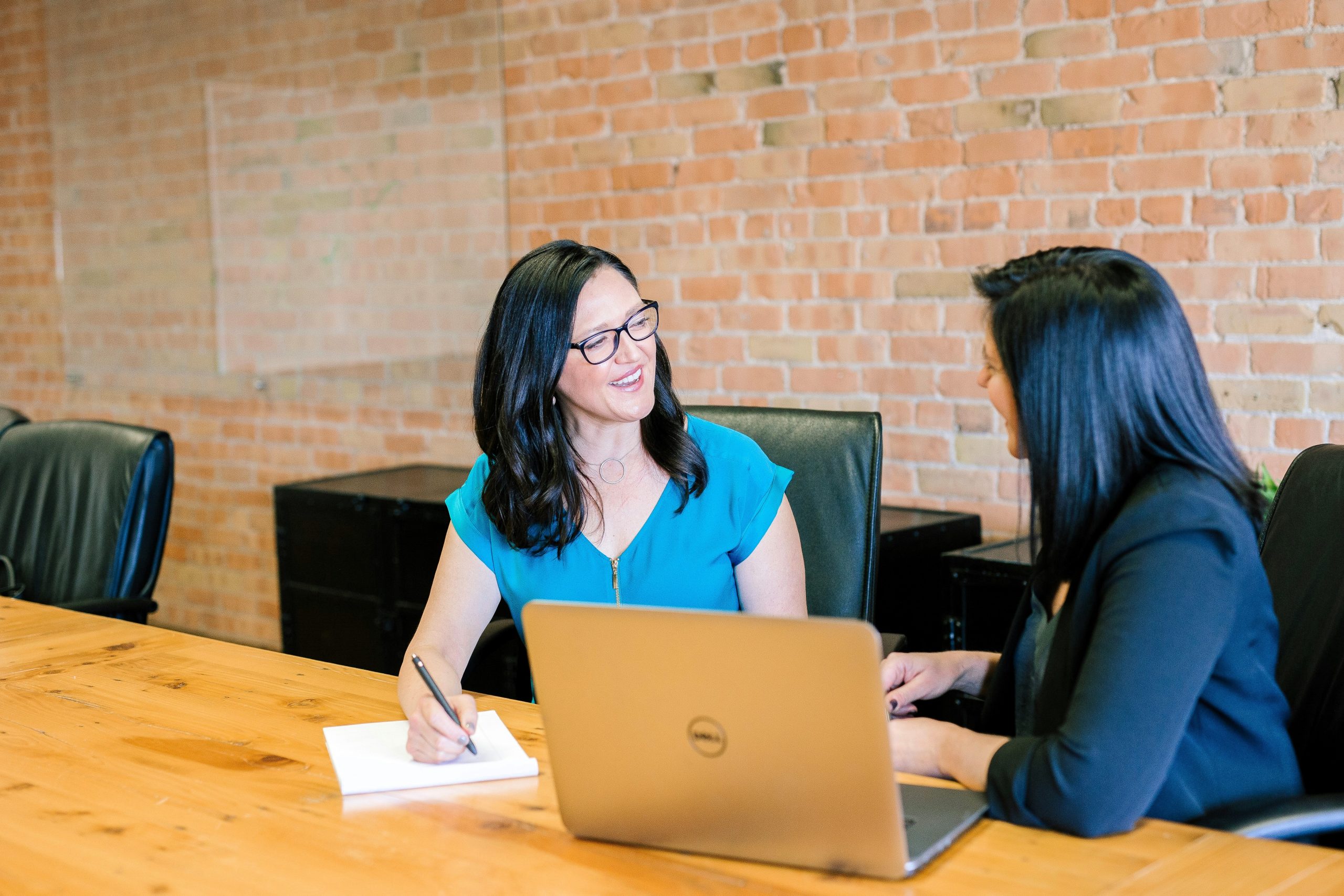 Soft skills para compliance officers, duas mulheres conversando em uma mesa em uma sala de reuniões